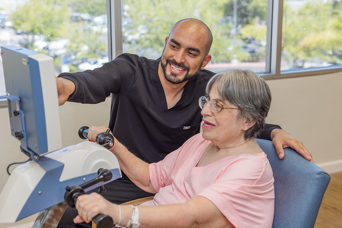 Country Hills facility rehab therapist helping a resident in the rehab gym